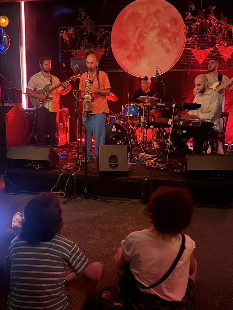 A live band performing beneath Dedaena's large red moon installation.