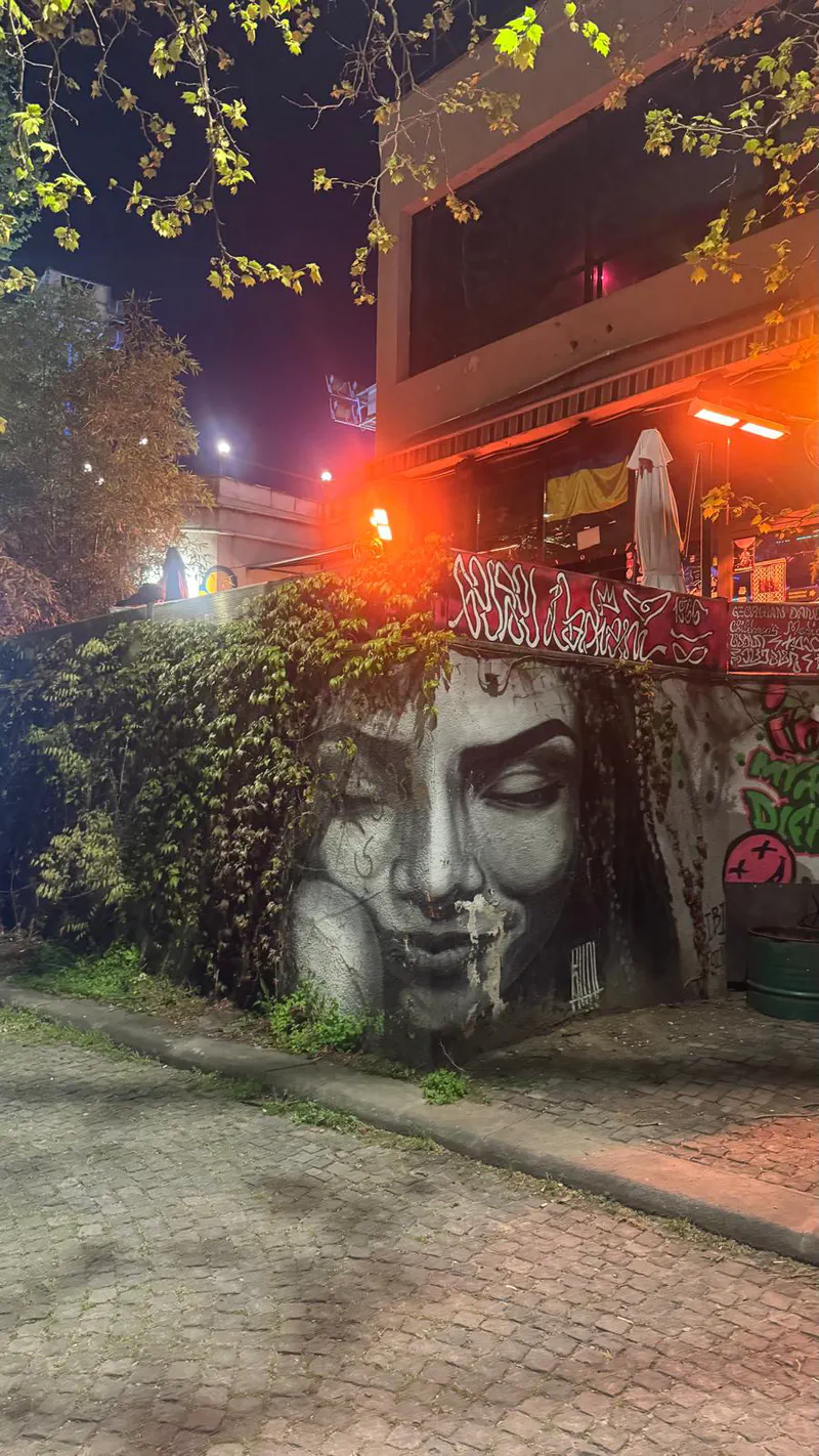 Dedaena's graffiti-covered exterior and terrace glowing orange at night.