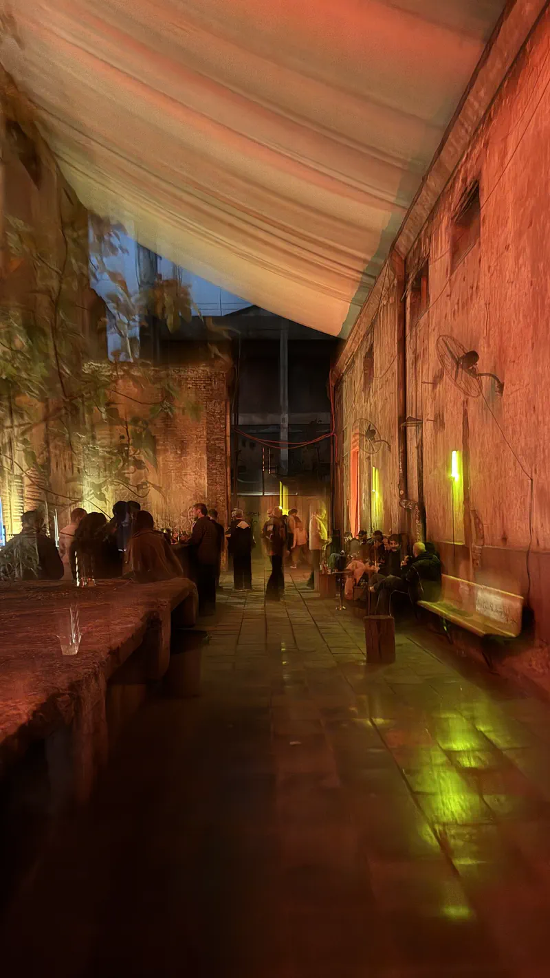 Guests socialising in a long covered courtyard under orange and yellow lights at Mutant Radio.