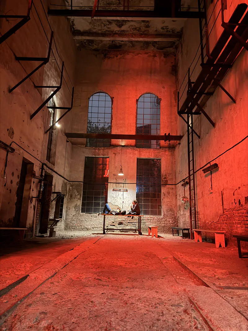 Mutant Radio's tall industrial hall lit red, with arched windows, exposed brick and simple benches.